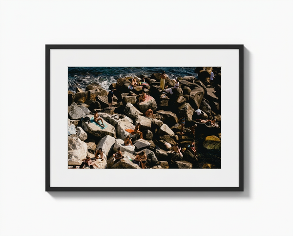 Framed photograph of a rocky shoreline with people on rocks.